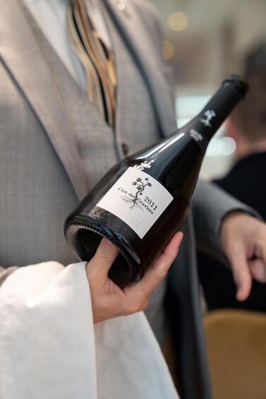 A person holding a wine bottle with a label that reads 'Clos des Graviers 2011.' 1