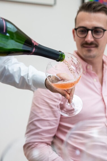 A person pouring a drink into a glass. 3