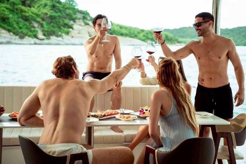 A group of people toasting with wine glasses on a boat with a view of a coastline. 2