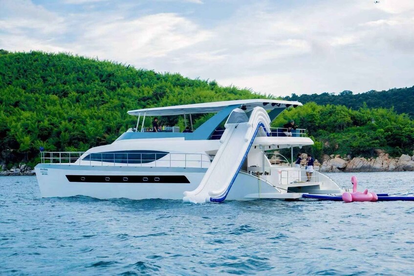 A white yacht with a slide on the deck, surrounded by water and greenery. 1