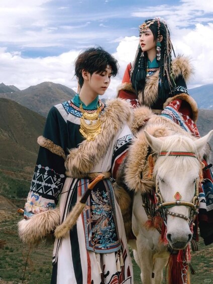 A person in traditional attire with a horse, set against a mountainous backdrop. 1