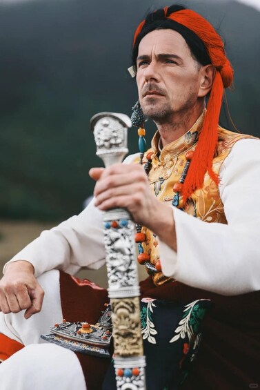 A person in traditional attire holding a decorated staff. 5