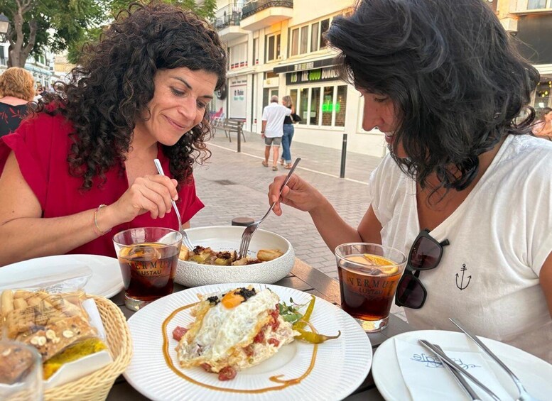 Two people dining outdoors with plates of food and drinks. 2