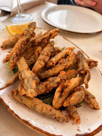 A plate of fried calamari with lemon wedges and a glass of wine. 3