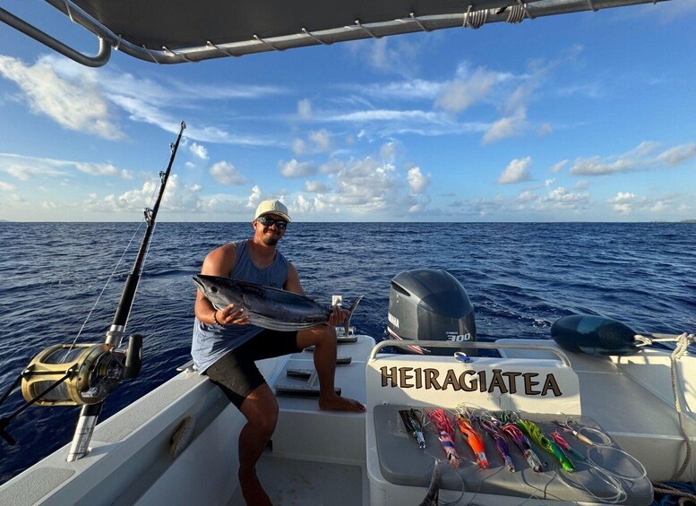A person on a boat holding a fish, with fishing rods and lures visible. 1