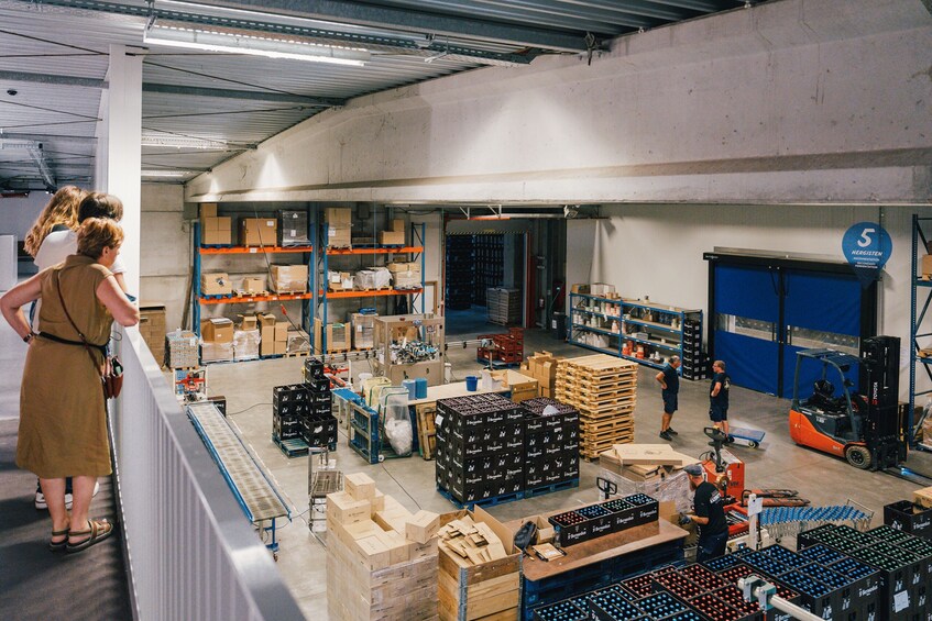A warehouse with shelves stocked with boxes, a forklift in operation, and people working. 2