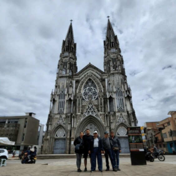 A Gothic cathedral with two spires, a group of people standing in front, and a cloudy sky. 2