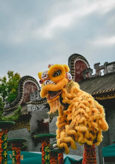 A traditional lion dance with a yellow lion head and costume, set against a backdrop of ornate Chinese architecture. 1