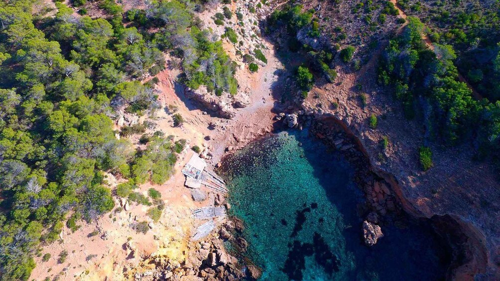 A coastal landscape with rocky terrain, clear blue waters, and dense green vegetation. 5