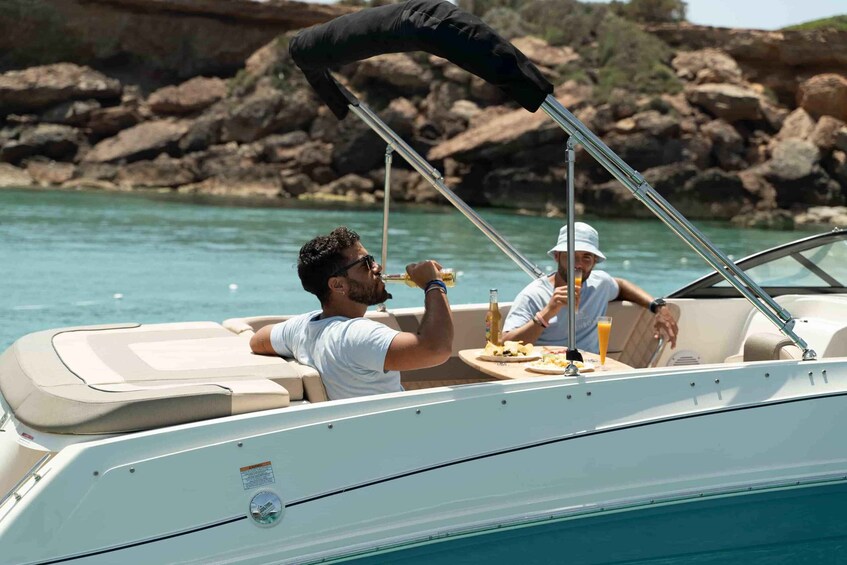 A boat with two people dining, surrounded by calm water and rocky cliffs. 4