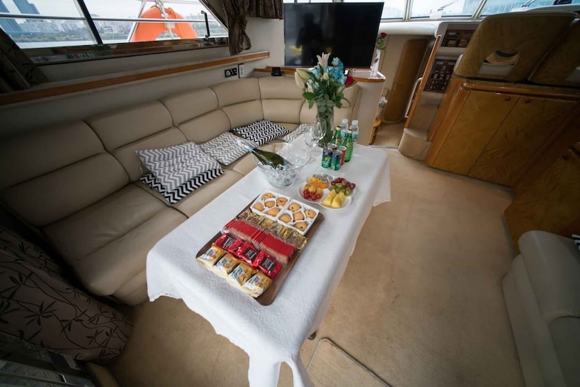 A yacht interior with a sofa, table with snacks, drinks, and a bouquet of flowers. 2