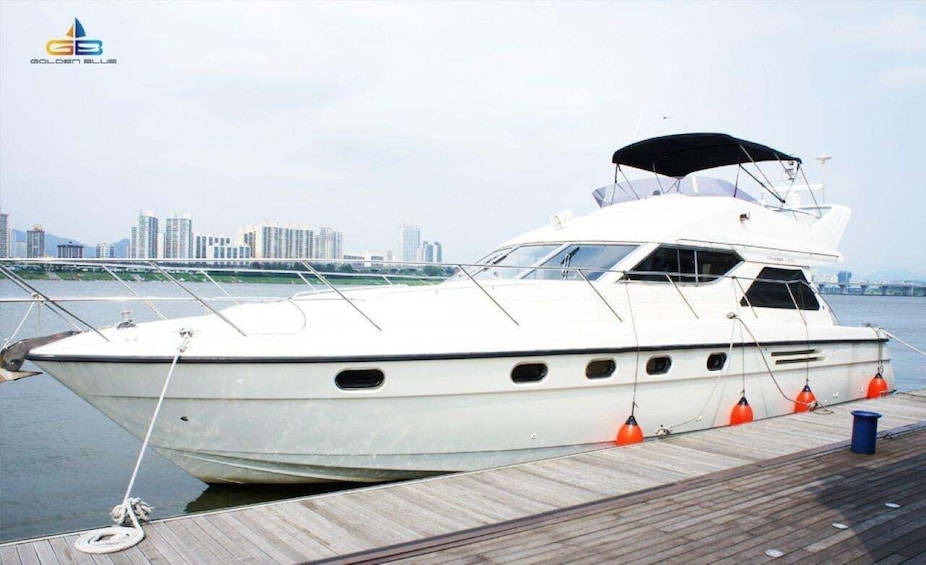 A white yacht docked at a pier with a city skyline in the background. 3