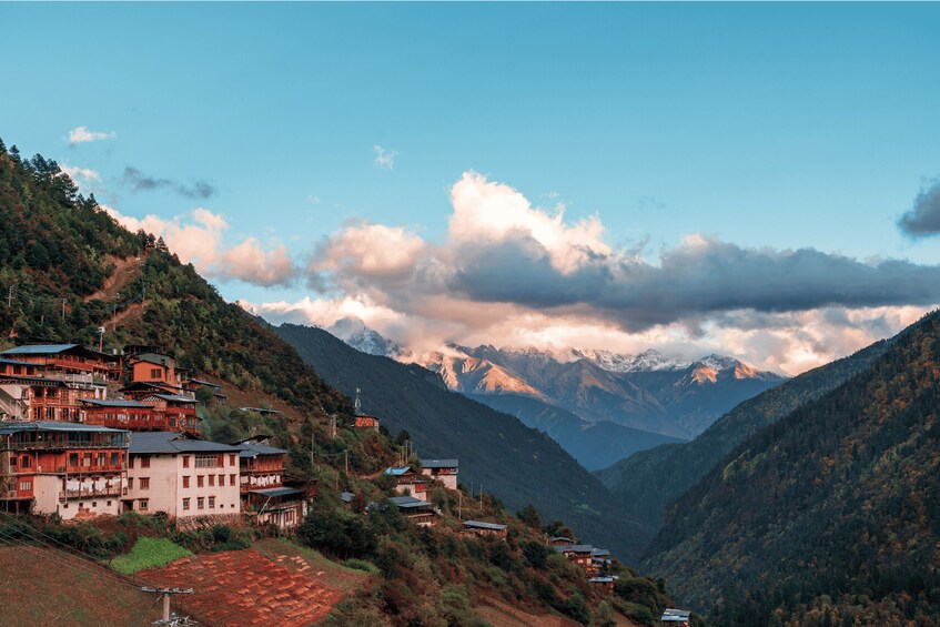 A mountainous village with traditional houses and a valley with snow-capped peaks. 1