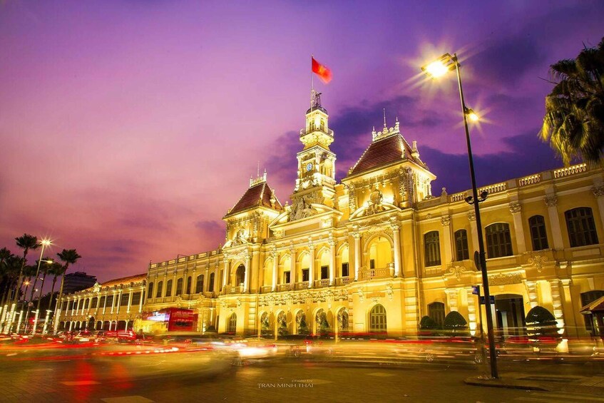 A grand, illuminated building with a prominent flag, surrounded by palm trees and streetlights. 2
