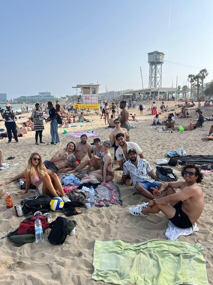 A crowded beach with people sunbathing and socializing, a lifeguard tower, and palm trees in the background. 3