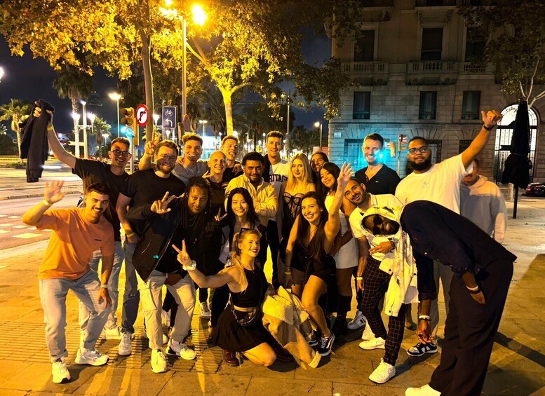 A group of people posing for a photo on a city street at night. 2