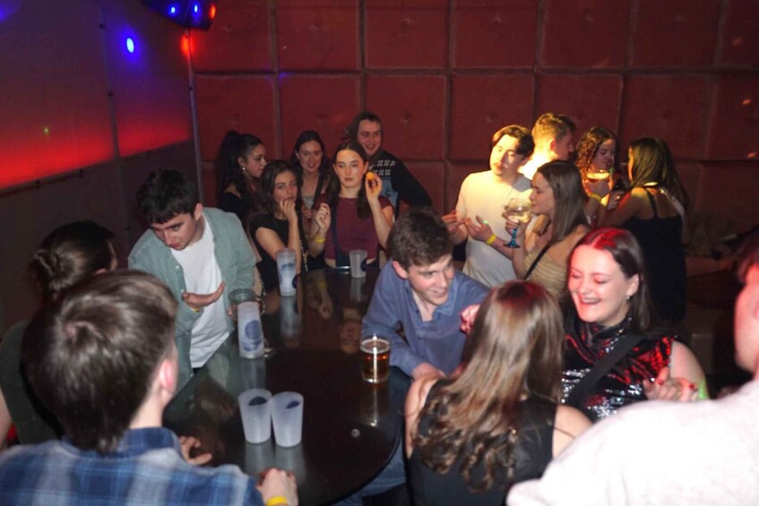 A group of people gathered around a table in a dimly lit indoor setting. 5