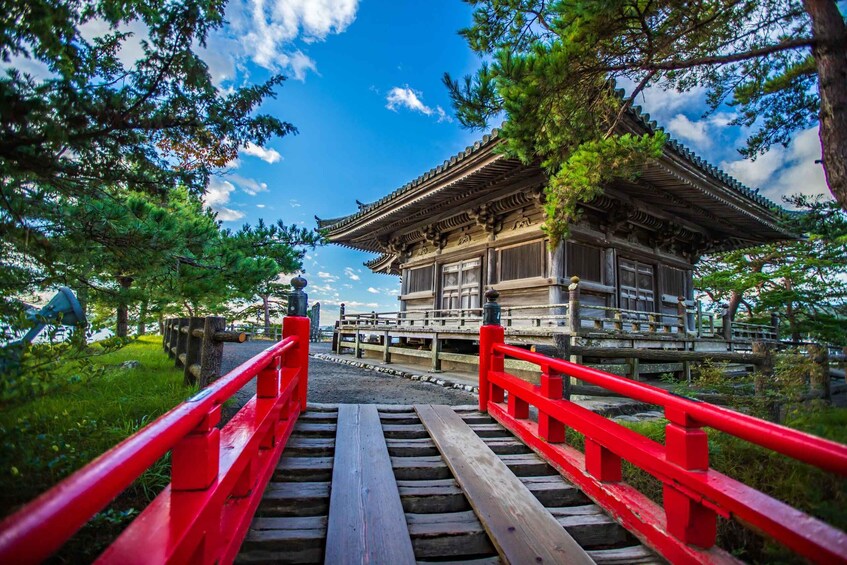A traditional Japanese building with a red bridge leading to it, surrounded by trees. 5