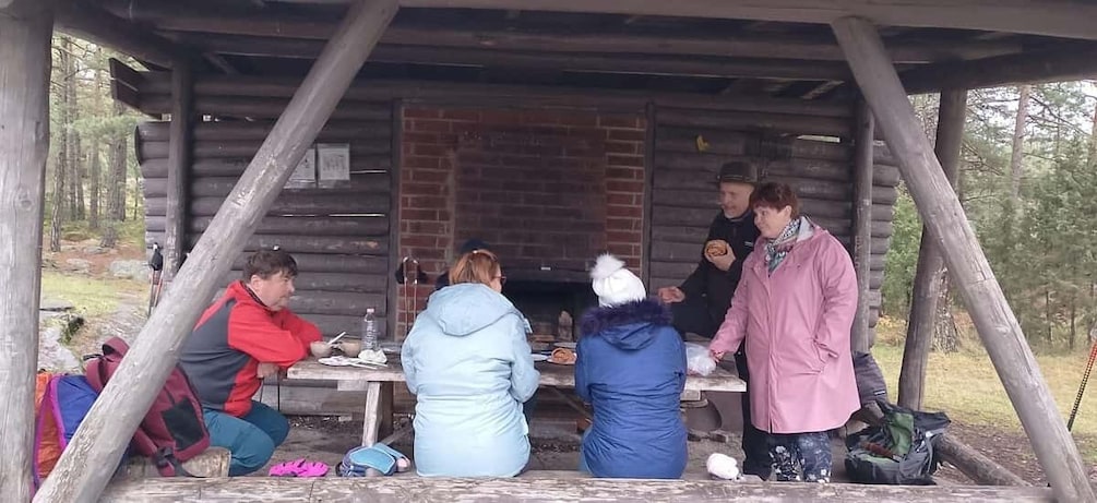 A group of people dining outdoors at a wooden cabin with a brick fireplace. 4