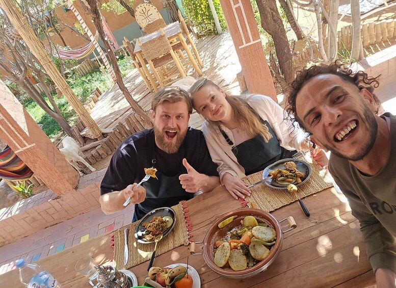 Three people dining outdoors with a variety of dishes on a wooden table. 2