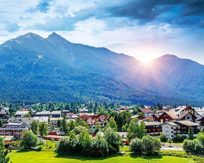 A mountain town with buildings and a sunlit mountain range. 4