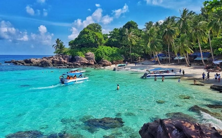 A turquoise beach with clear water, palm trees, and boats. 3