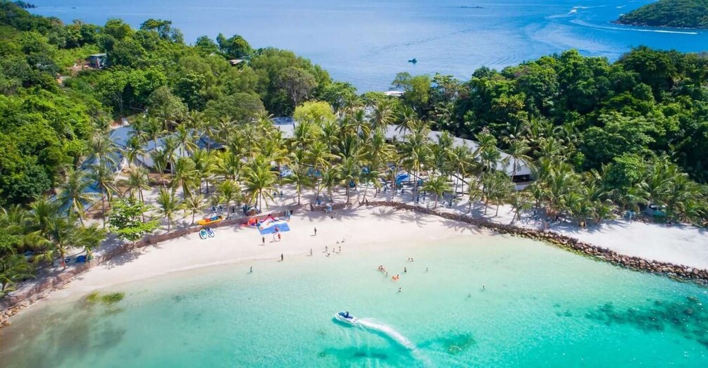 A tropical beach with clear turquoise waters, palm trees, and a few people swimming. 4