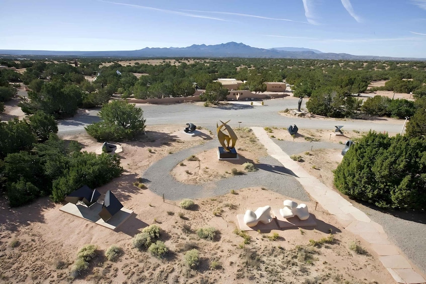 A desert landscape with scattered trees, a winding road, and a distant mountain range. 2
