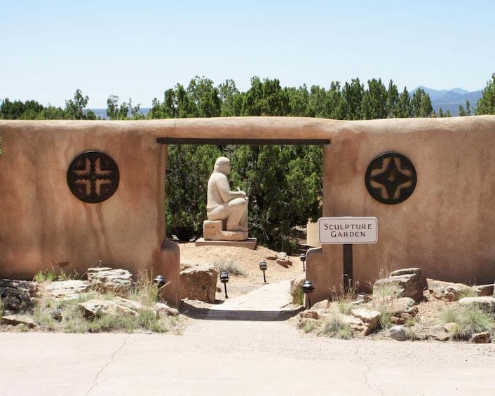 A sculpture garden entrance with a stone statue and a sign. 1