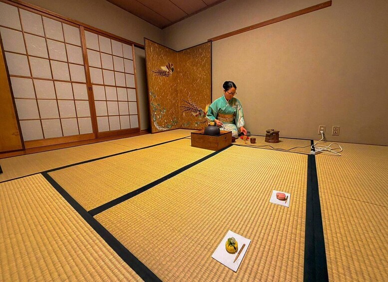 A traditional Japanese room with tatami flooring, a shoji screen, and a person in kimono. 5