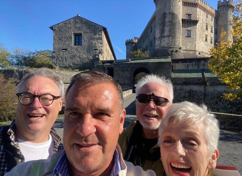 A group of people in front of a historic stone building with a tower. 2