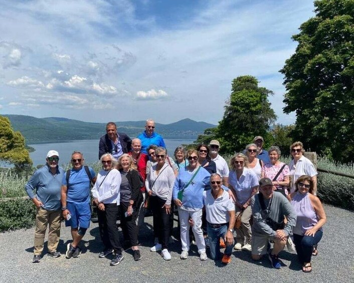 A group of people standing on a path by a lake with mountains in the background. 5