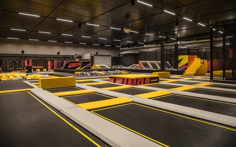 An indoor trampoline park with multiple trampolines and padded obstacles. 3