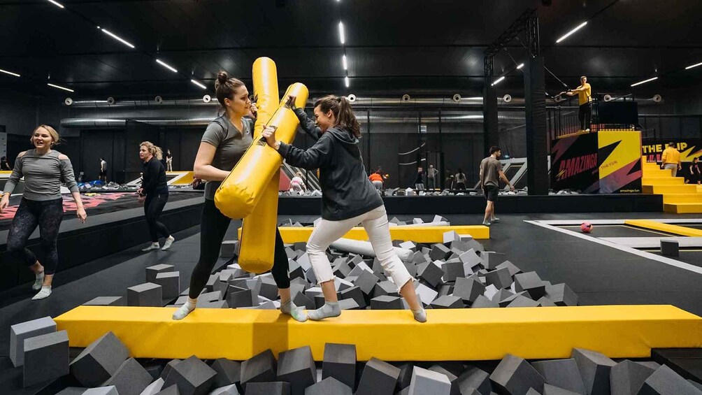 An indoor obstacle course with participants navigating through foam blocks and a yellow punching bag. 1
