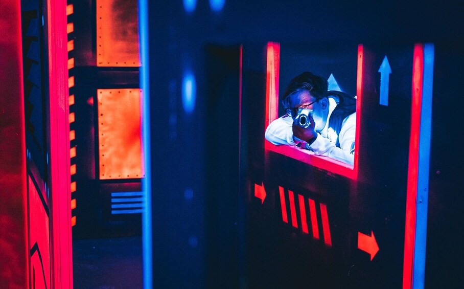 A person in a red-lit room with directional arrows on the walls. 2