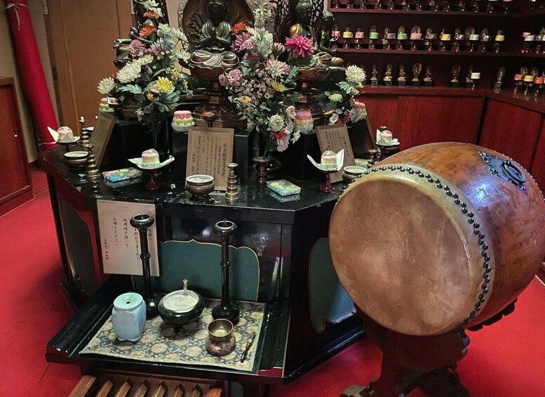 A traditional altar with a seated Buddha statue, incense burners, and offerings. 5