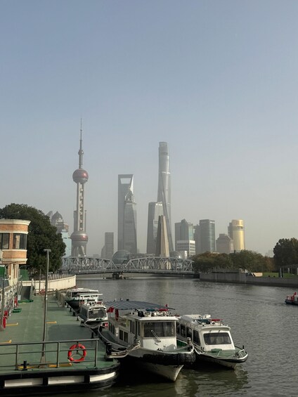 A river with boats docked, a bridge, and a city skyline with tall buildings. 5