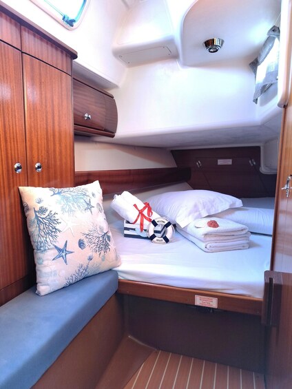 A compact cabin with a bed, a wooden cabinet, and a small seating area with a decorative pillow. 2