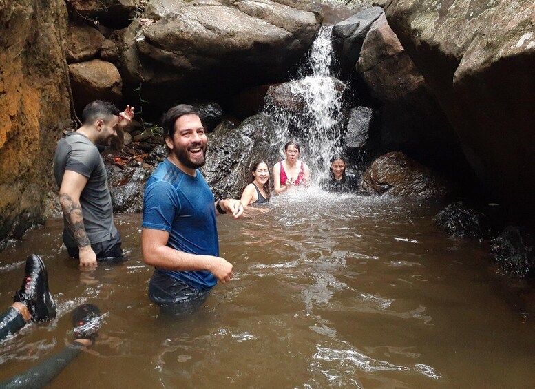 A group of people wading in a rocky stream with a waterfall. 1