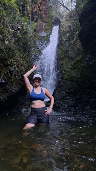 A person standing in a stream with a waterfall in the background. 2
