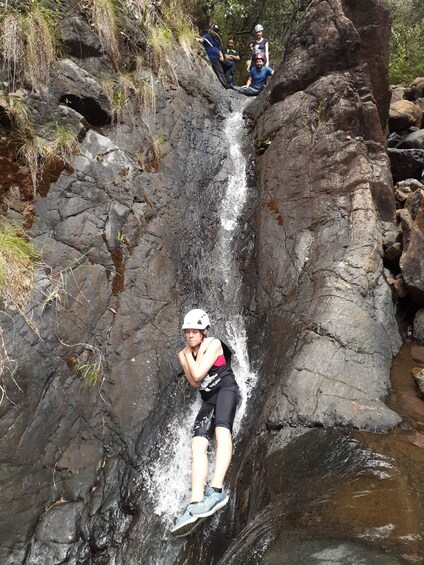 A person rappelling down a rocky waterfall. 5