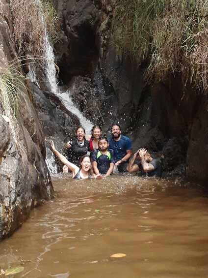 A group of people in a shallow water body with a waterfall. 4