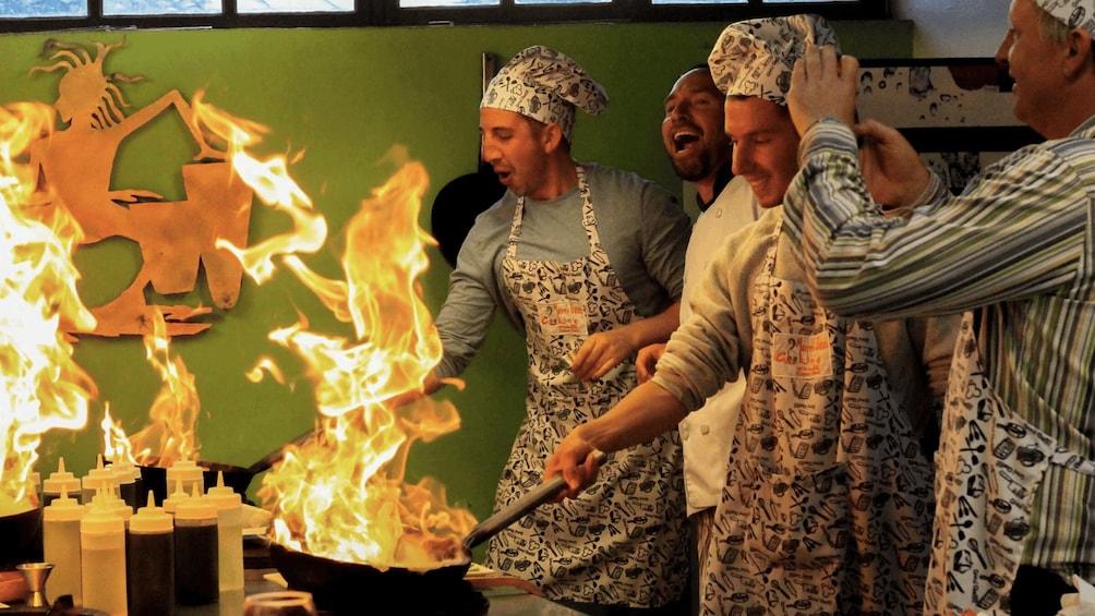 Chefs cooking with flames, wearing aprons and chef hats. 1
