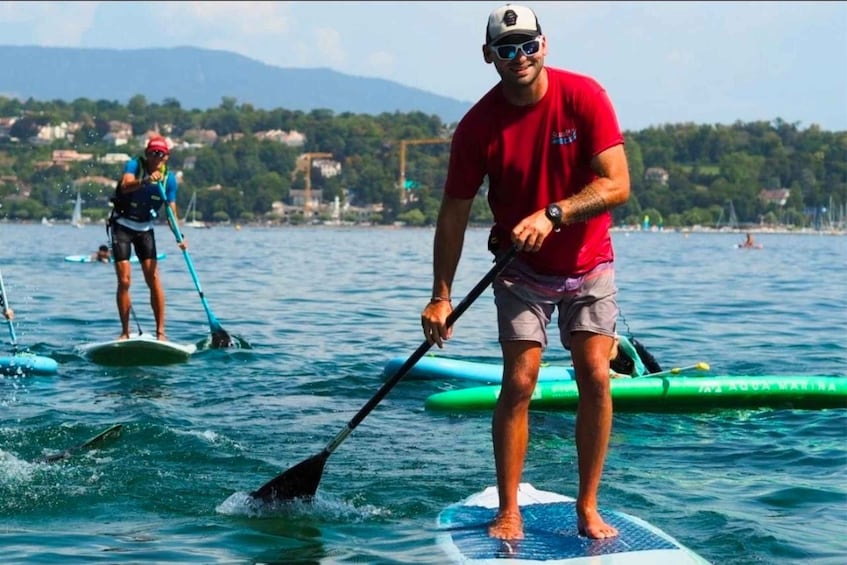 Two people paddleboarding on a calm sea with a mountainous landscape in the background. 1