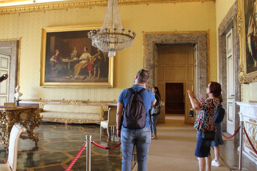 A grand room with a large painting, ornate furniture, and a chandelier. 2