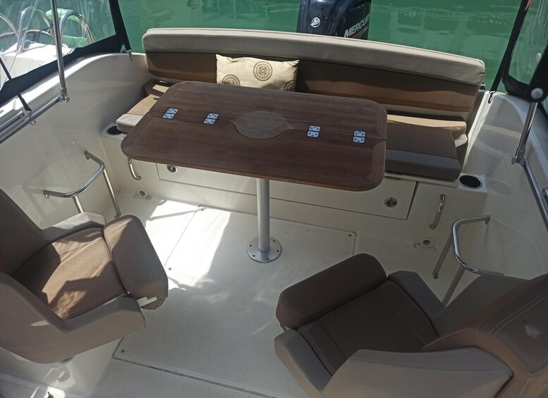 A boat interior with a wooden table, cushioned seating, and a small storage compartment. 2