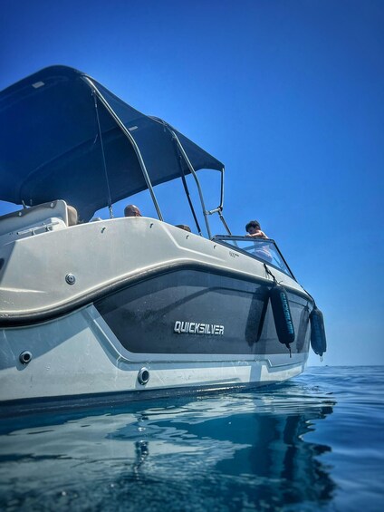 A white motorboat with a blue canopy, labeled 'QUICKSILVER,' on calm water. 4