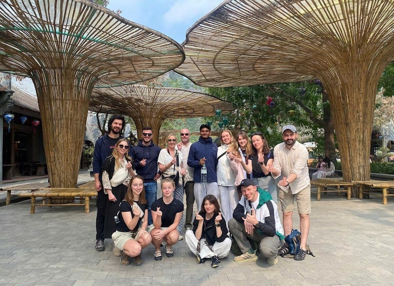 A group of people posing under bamboo structures in an outdoor setting. 5