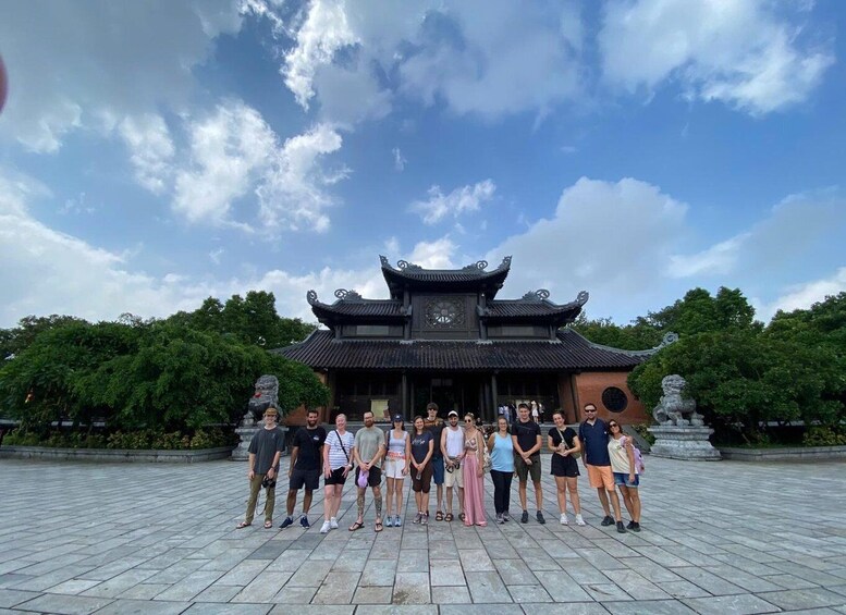 A group of people standing in front of a traditional building with a tiled roof and a clock. 3