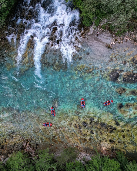 A clear river with a waterfall, rocky terrain, and kayaks. 4